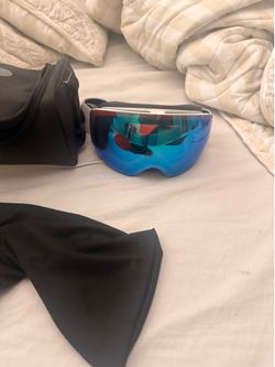 Oakley Flight Deck snow goggles, featuring a prominent blue mirrored lens and a white strap.