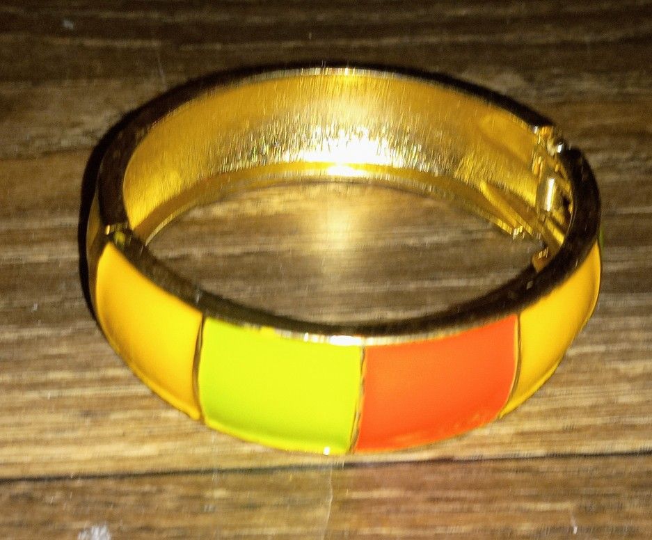 Add a playful touch to your outfit with this Rubik's Cube patterned bangle bracelet. Featuring vibrant colored squares in yellow, green, orange, and r