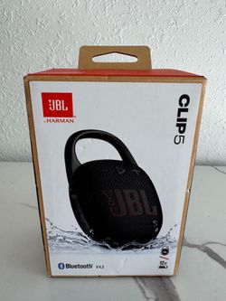 New JBL Clip 5 portable Bluetooth speaker. Speaker is black color. Has Bluetooth V5.3, IP67 waterproof and dustproof. Provides up to 12 hours playtime