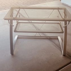 Modern glass-top computer desk with a curved silver metal frame and a pull-out keyboard tray.