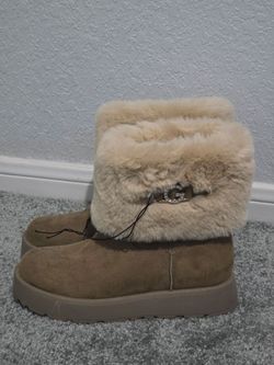 These tan GBG Guess boots feature a faux shearling fur cuff and a gold-accented "G" logo