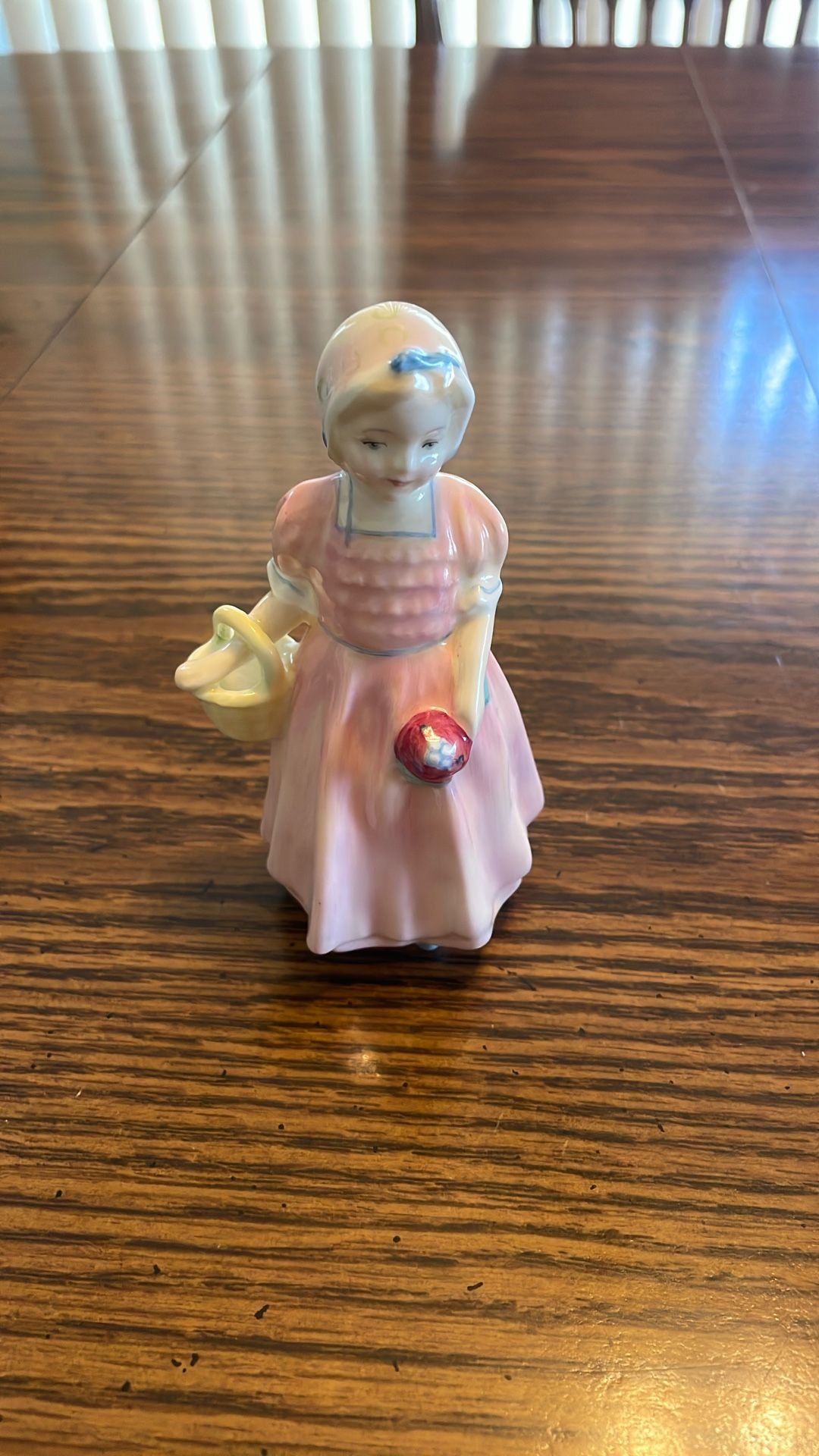 Royal Doulton “Tinker Bell”. 4 5/8 Inches. Girl In Pink Dress Carrying A Basket And A Bouquet of Flowers”