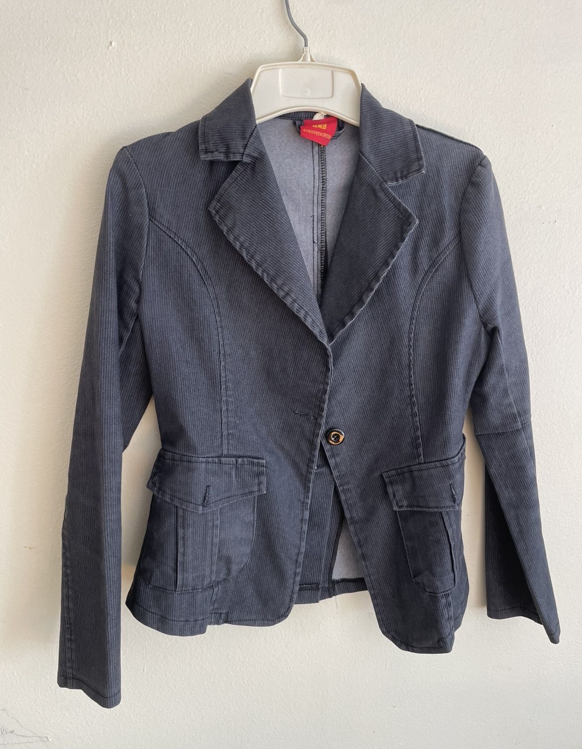 A slim-fit women's blazer in a deep grey (or charcoal black) color. • Fabric texture: The surface has distinct fine vertical stripes, resembling cordu
