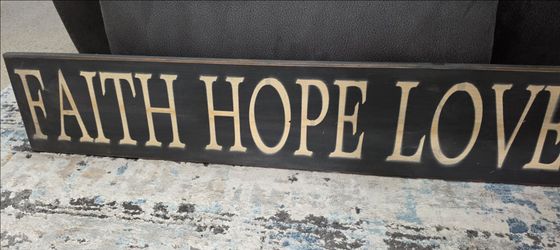 wooden wall plaque features the phrase "FAITH HOPE LOVE," a popular inspirational quote