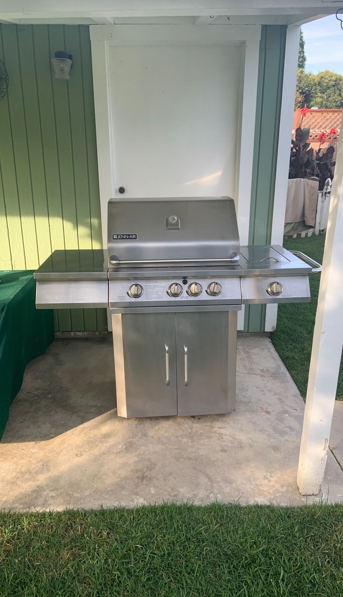 Stainless steal JennAir BBQ with stainless grills and a canvas cover