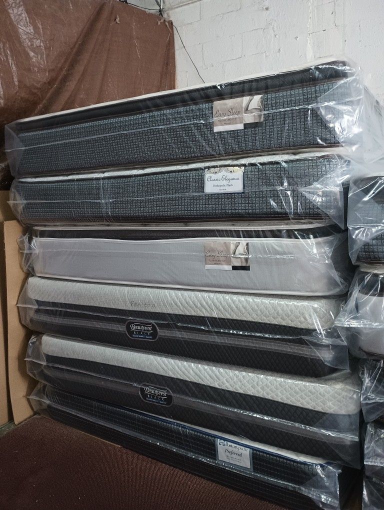 Have All Size Available Good Prices Todos Los tamaños Disponibles Stack of new mattresses wrapped in protective plastic. Multiple styles available.