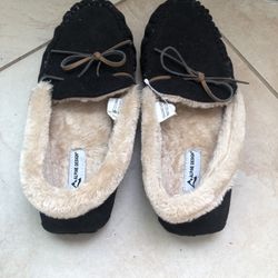 “Alpine Design” Two pair of black, faux-fur-lined moccasin-style slippers with decorative leather laces.  