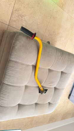curved yellow metal parent training push bar/guide handle for a kid's bicycle or tricycle.