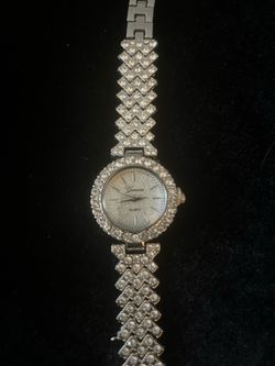 Sparkly watch has silver tone finish. Round face with rhinestone bezel. Band is covered in rhinestones. Watch has 'Geneva' brand on face and 'QUARTZ' 