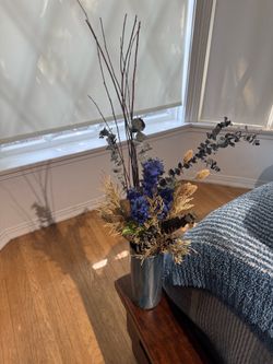 decorative dried floral arrangement in a metallic blue cylinder