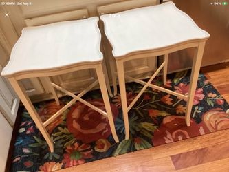 Distressed white tray tables with a decorative, scalloped edge and an X-cross leg design. This style is commonly associated with shabby chic, farmhous