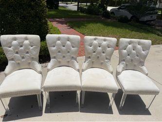 Four white velvet padded chairs with clear legs