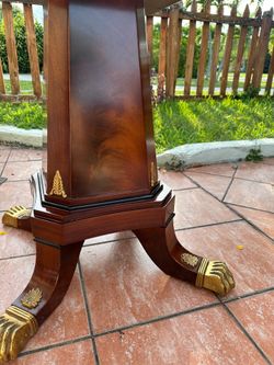 Regency-style pedestal table featuring figured mahogany and brass claw feet