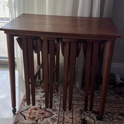 The set includes one large rectangular table on casters and four smaller, round, drop-leaf tables that store neatly underneath.  