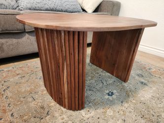Oval wood coffee table with fluted base.
