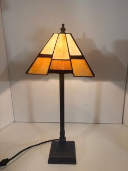 Tiffany-style Mission accent table lamp featuring a geometric amber stained glass shade and a dark metal base 18” tall