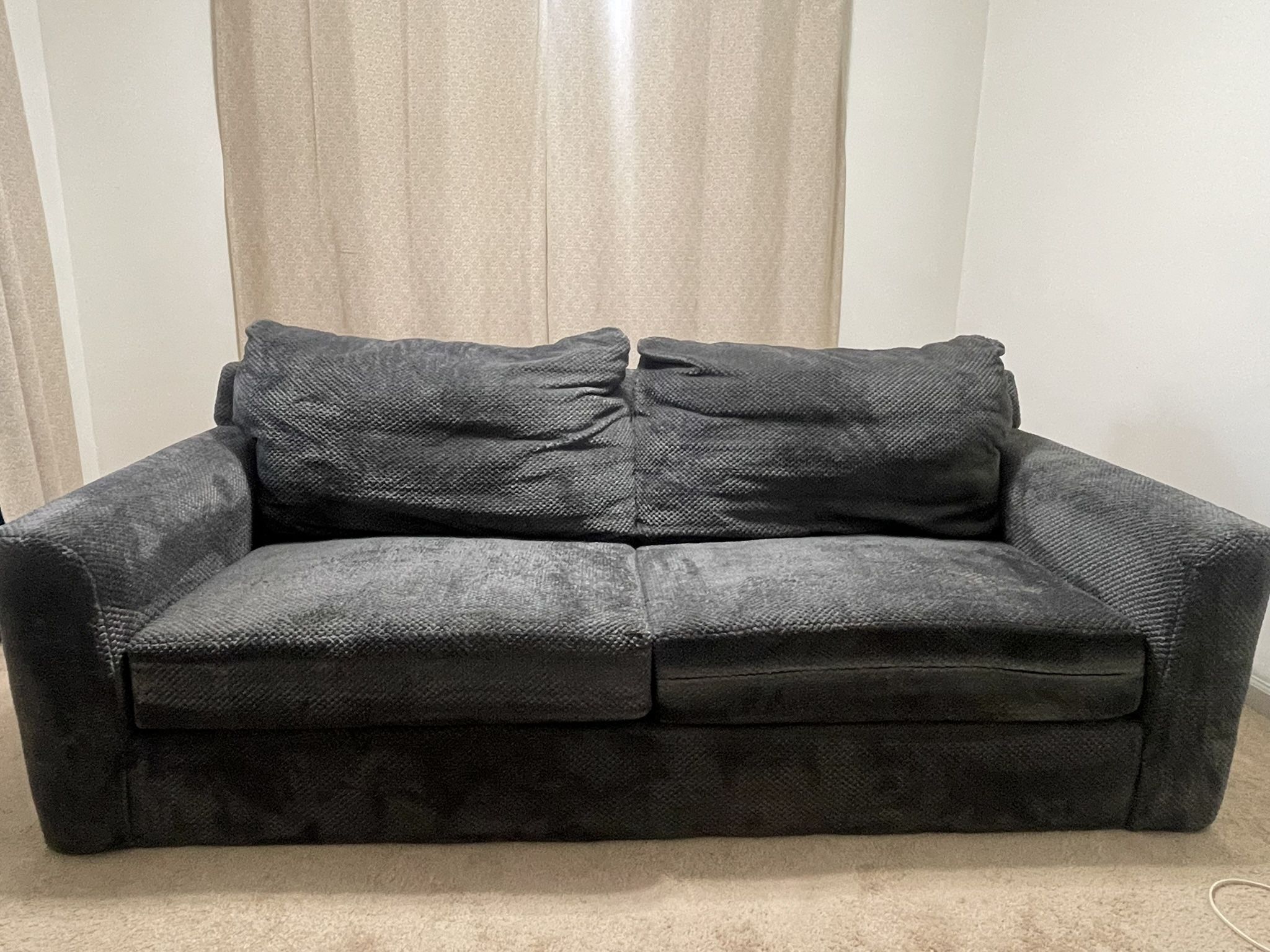 Modern dark gray 2-seater sofa with plush cushions and textured upholstery. 