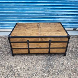 Industrial trunk style coffee table. Top slides open for storage. Measures approx: 42" wide 