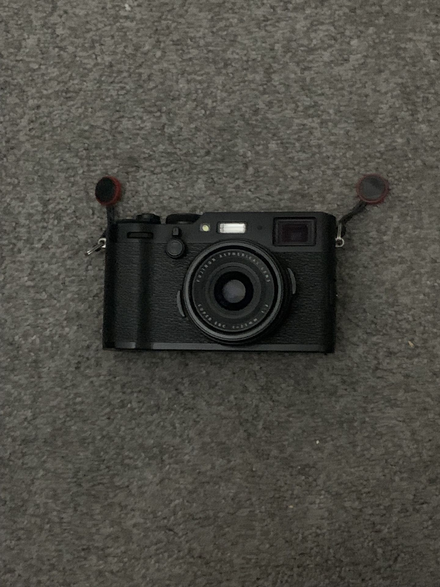 black fujifilm x100f with light, tripod, and strap