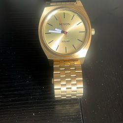 gold-toned Nixon Time Teller Solar watch with a matching 5-link stainless steel bracelet.