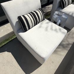Two white chairs with pillows