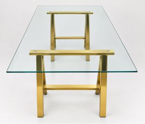 Glass & Gold Dining Table – 66” x 38”  Beautiful modern dining table featuring a clear glass tabletop with a polished gold/brass metal frame.