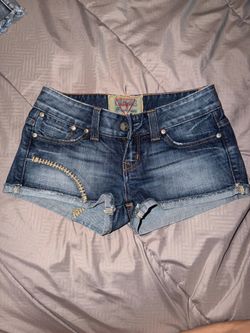 Guess blue denim cutoff shorts featuring a distinctive embroidered design along the back pockets and raw hem size 24