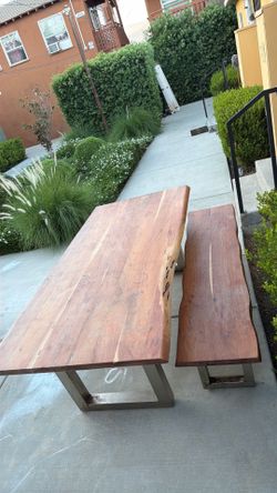 Custom live-edge solid wood dining table with matching bench and welded steel legs.