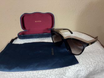 Gucci GG0163S sunglasses featuring a shiny black frame and gold-toned interlocking G logo.