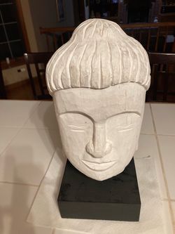 white-finished, hand-carved wooden Buddha bust sculpture is mounted on a solid black rectangular base.Material & Finish: Expertly hand-carved from sus