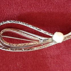 Silver tone brooch with scroll design and pearl.
