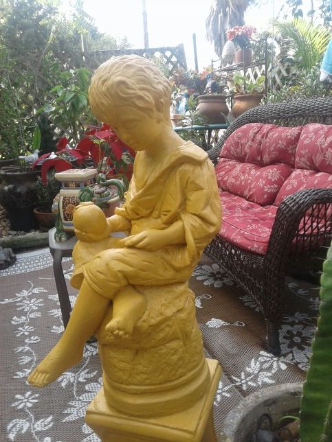 Vintage boy sitting on a pedestal with an apple all concrete