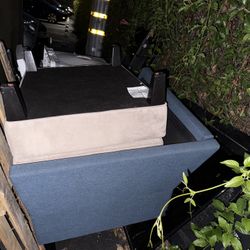 Blue upholstered chair w/o cushions and beige upholstered ottoman. 