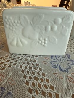 1 white ceramic napkin holder featuring an embossed fruit and grape pattern.
