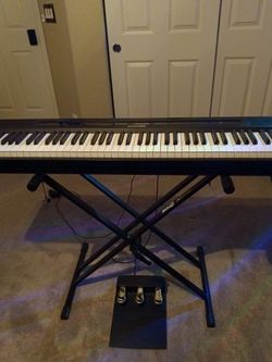 Black keyboard with weighted keys a foot pedal and stand and different functions and headphones