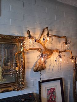Sculptural chandelier with a gold tree-branch design and crystal drops.
