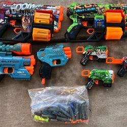 collection of toy dart blasters and foam darts from the Zuru X-Shot and Nerf brands.
