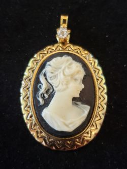 $8. Cameo inspired gold tone pendant. Pendant is 1 3/4-in long. And 1-in wide.