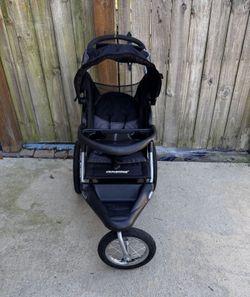 Baby’s Trend Expedition Jogger stroller. The stroller is a three-wheeled jogging stroller with a large canopy and a storage basket underneath. The fro