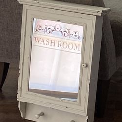 Pre-owned distressed shabby chic white wooden medicine cabinet with a mirror and towel hooks.
