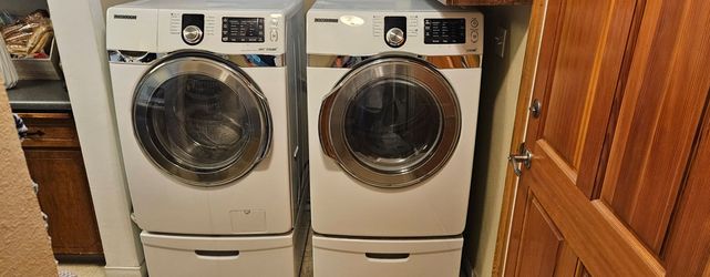 Samsung washer and electric dryer with pedestals.