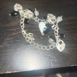 This product is a charm bracelet, similar in style to gothic or handmade jewelry featuring black beads and silver heart-shaped padlock charms. 