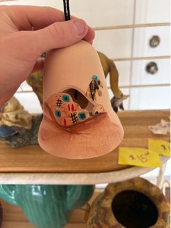 handmade Native American style Southwestern pottery bell featuring pueblo cliff dwelling imagery, a turquoise stone, and a feather bundle