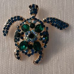 Turtle-shaped brooch gold tone with green stones.
