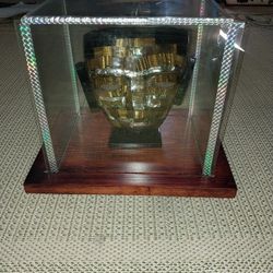 Stone mask on wood stand in glass case made in mexico