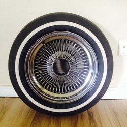 One 14" knock off rim with tire that has 50% tread