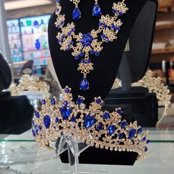 Gold-toned regal tiara with upsidedown blue teardrop gemstones and rhinestone accents, matching necklace/earrings