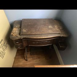 Antique wooden treadle sewing machine cabinet with ornate carvings.