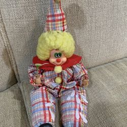 Vintage wind-up musical clown doll with plaid clothing and yellow hair.
