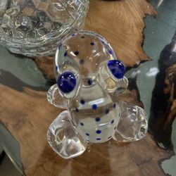 Art glass paperweight frog is clear glass with blue eyes and spots. He is signed on the bottom as shown in the pictures and made in Poland.